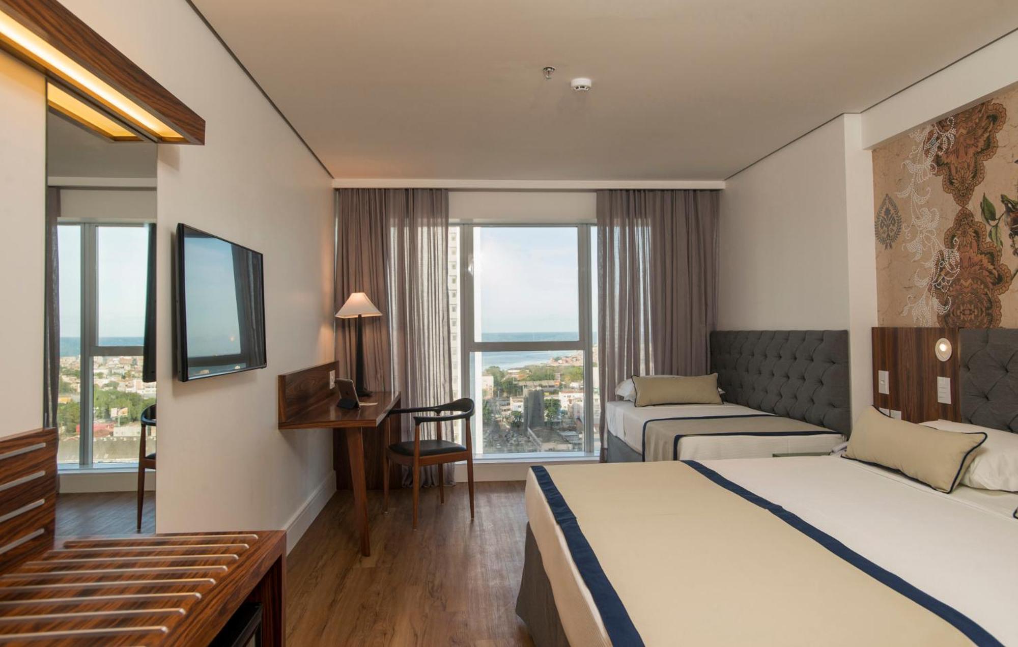 Hotel Luzeiros Ресифи Экстерьер фото The photo shows a hotel room that features a modern and comfortable design. There are two beds: one larger bed and a smaller twin bed. The room has large windows with curtains that allow natural light to enter, offering a view of the outside, possibl